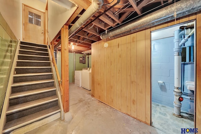 unfinished below grade area featuring electric panel, separate washer and dryer, and stairs