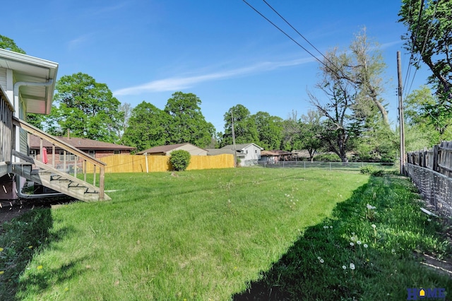 view of yard with a fenced backyard and stairs