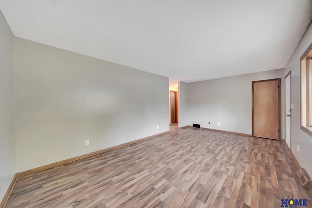 unfurnished room with baseboards, light wood-type flooring, and visible vents