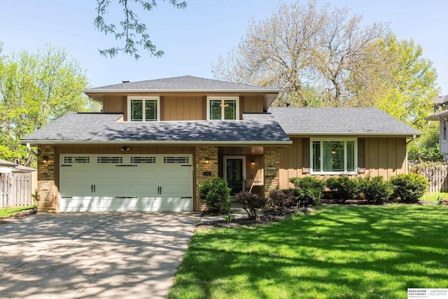 split level home with fence, a front lawn, board and batten siding, roof with shingles, and driveway