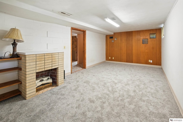 finished below grade area with baseboards, visible vents, wooden walls, a fireplace, and carpet floors