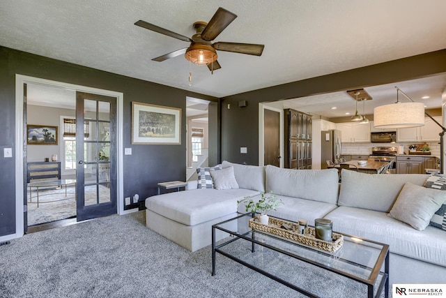 living area featuring ceiling fan, healthy amount of natural light, carpet flooring, and baseboards