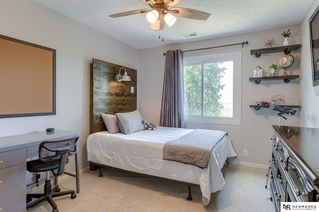bedroom featuring light colored carpet, baseboards, an office area, a textured ceiling, and ceiling fan
