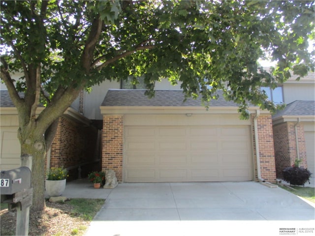 obstructed view of property featuring brick siding and concrete driveway