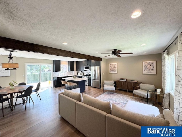living room with a textured ceiling, light wood-style floors, ceiling fan, and recessed lighting
