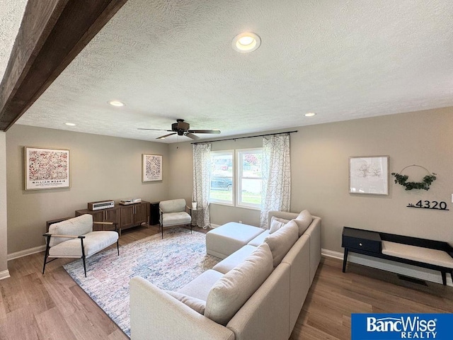 living room featuring baseboards, a textured ceiling, ceiling fan, recessed lighting, and light wood finished floors