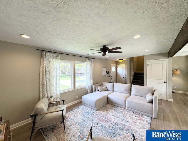 living room with a textured ceiling, baseboards, recessed lighting, wood finished floors, and stairway