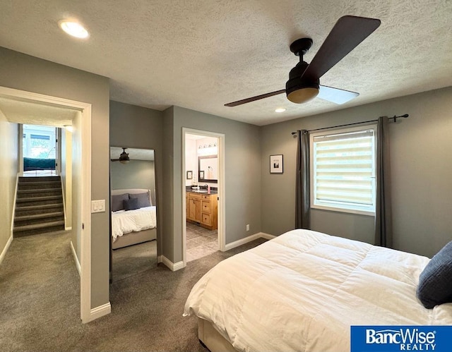bedroom featuring a textured ceiling, dark colored carpet, connected bathroom, ceiling fan, and baseboards