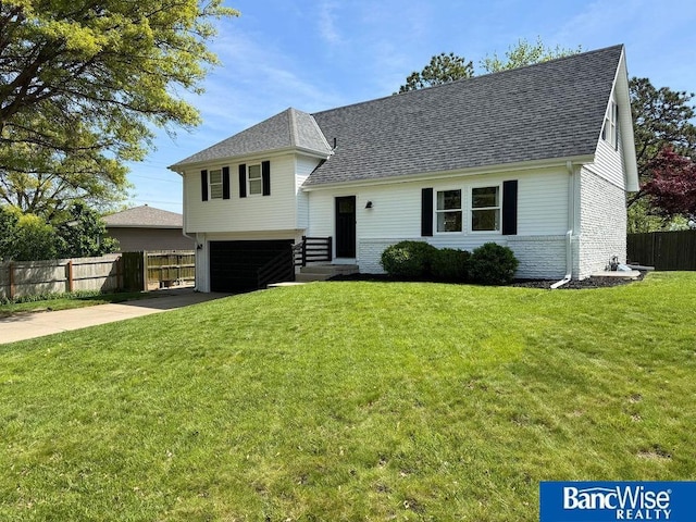 tri-level home with an attached garage, roof with shingles, concrete driveway, and brick siding
