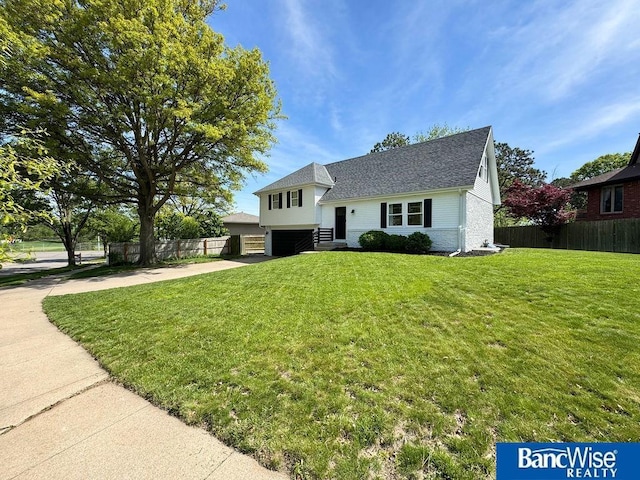 tri-level home featuring a garage, driveway, and roof with shingles