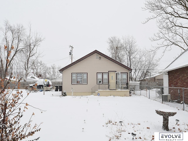 snow covered house with fence and cooling unit