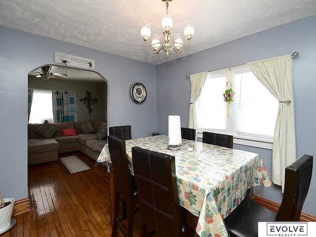 dining room featuring a chandelier, hardwood / wood-style floors, a textured ceiling, arched walkways, and a ceiling fan