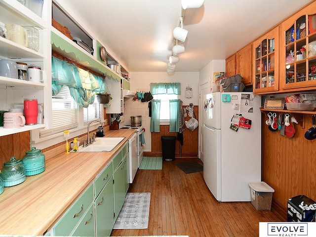 kitchen with white appliances, a sink, light countertops, wood-type flooring, and green cabinets
