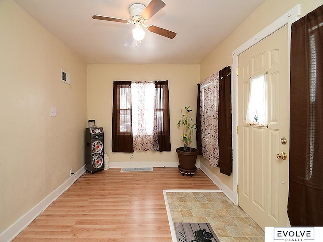 foyer entrance featuring a ceiling fan, light wood-style flooring, and baseboards
