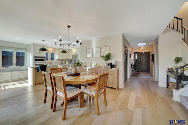 dining room featuring stairs, light wood-style floors, and a chandelier