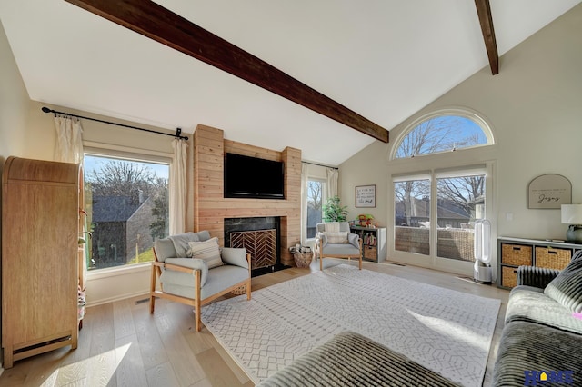 living room with beam ceiling, healthy amount of natural light, light wood finished floors, a fireplace, and high vaulted ceiling