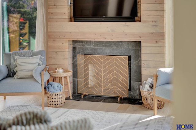 detailed view of a tiled fireplace, wood finished floors, and wooden walls