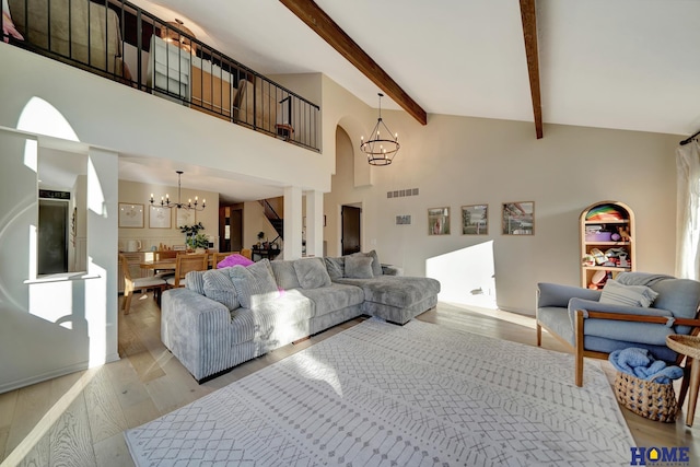 living room with a chandelier, light wood finished floors, beam ceiling, arched walkways, and high vaulted ceiling