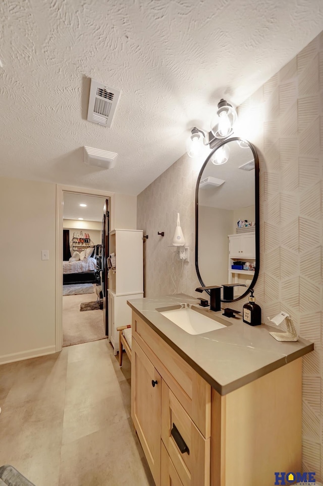 bathroom with a textured ceiling, vanity, and ensuite bath