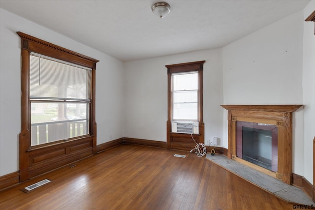 409 N 25th St, Lincoln, NE 68503 - unfurnished living room featuring wood-type flooring, a fireplace with flush hearth, baseboards, and cooling unit