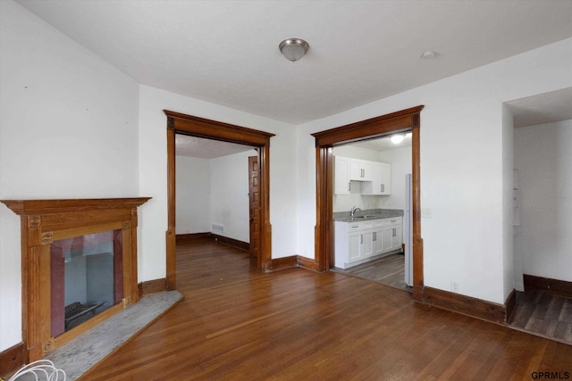 409 N 25th St, Lincoln, NE 68503 - unfurnished living room with baseboards, dark wood-type flooring, and a sink
