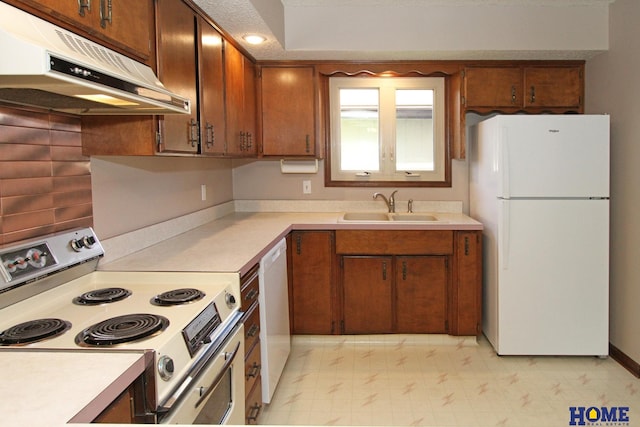 kitchen with freestanding refrigerator, electric range oven, under cabinet range hood, a sink, and dishwashing machine