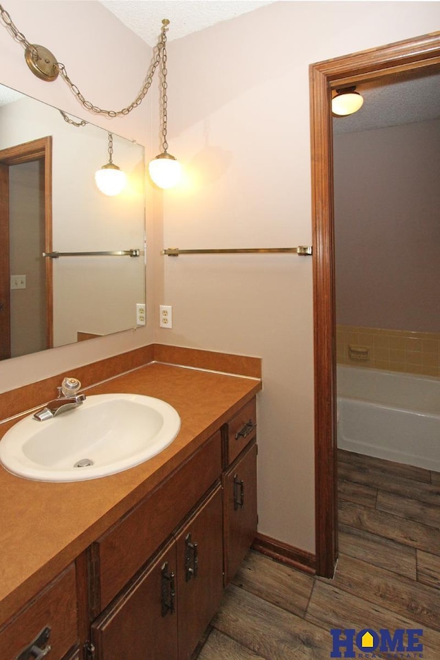 full bathroom featuring wood finished floors, vanity, and a tub to relax in