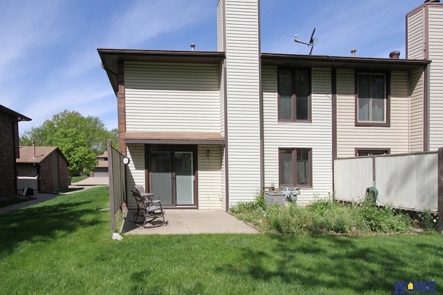 rear view of house featuring a chimney, a yard, and a patio area