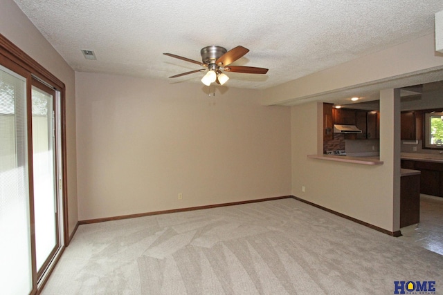 unfurnished room with a ceiling fan, light colored carpet, a textured ceiling, and baseboards