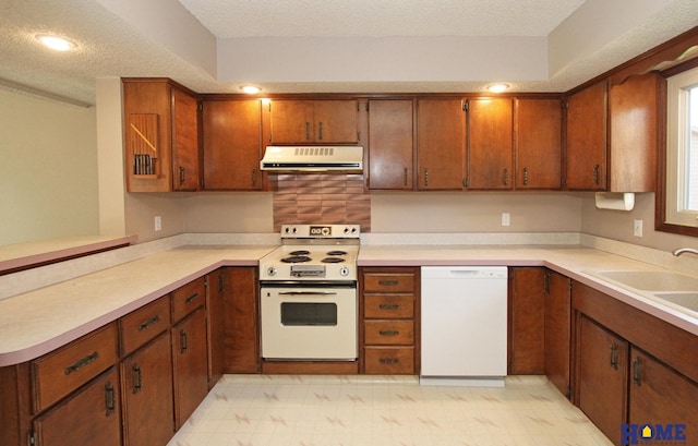 kitchen featuring white appliances, exhaust hood, a textured ceiling, light countertops, and a sink