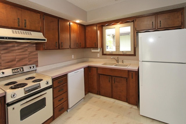 kitchen with white appliances, under cabinet range hood, a sink, light countertops, and light flooring