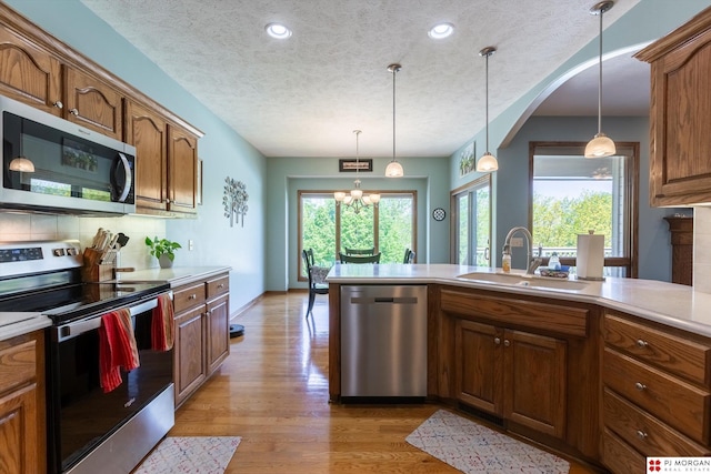 kitchen featuring stainless steel appliances, a textured ceiling, a sink, light countertops, and recessed lighting