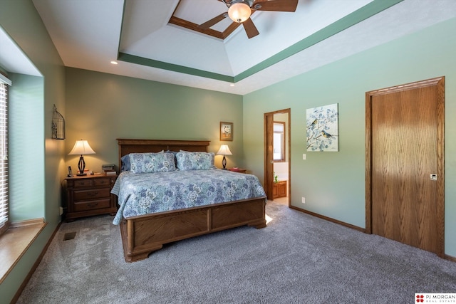 bedroom with carpet flooring, a tray ceiling, baseboards, and a ceiling fan