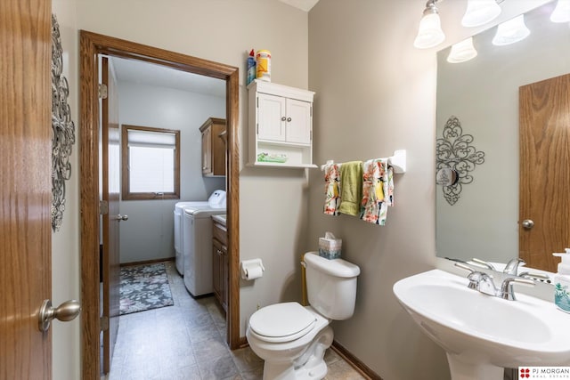 half bathroom with washer and clothes dryer, a sink, toilet, and baseboards