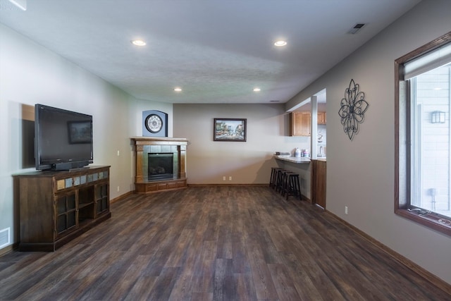 living area with dark wood finished floors, recessed lighting, a tiled fireplace, and baseboards
