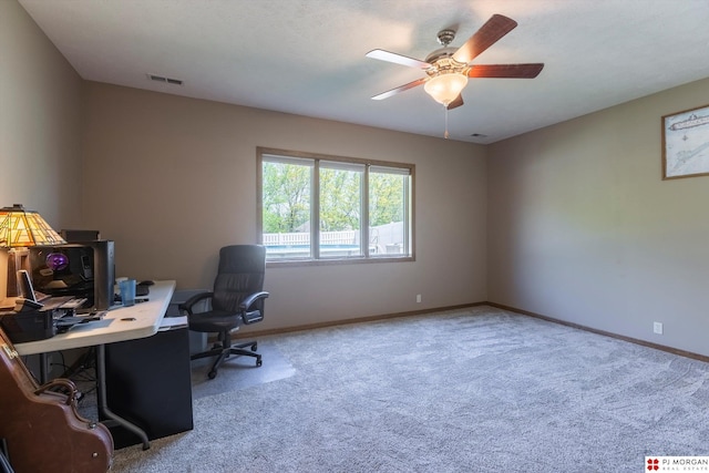 carpeted office space featuring ceiling fan and baseboards