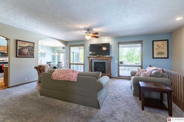 living area with arched walkways, ceiling fan, light colored carpet, a chandelier, and baseboards