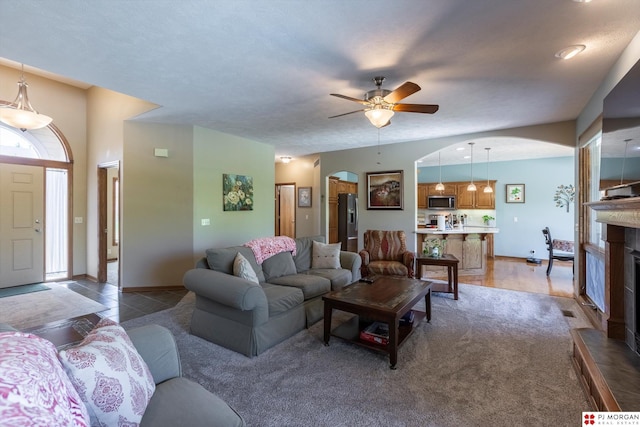 living area featuring arched walkways and ceiling fan