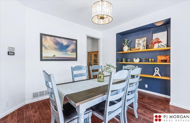 dining room featuring an inviting chandelier, baseboards, visible vents, and wood finished floors