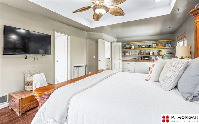 bedroom featuring wood finished floors, a raised ceiling, and ceiling fan