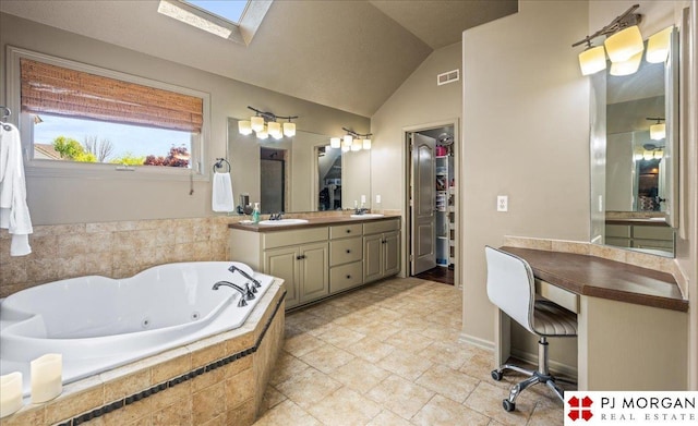 bathroom with a tub with jets, a walk in closet, vaulted ceiling with skylight, visible vents, and vanity