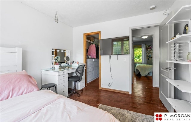bedroom with a closet, wood finished floors, and a walk in closet