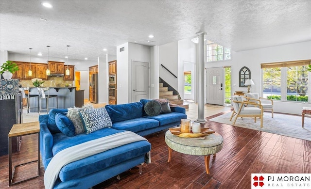 living area with stairs, lofted ceiling, decorative columns, a textured ceiling, and light wood finished floors