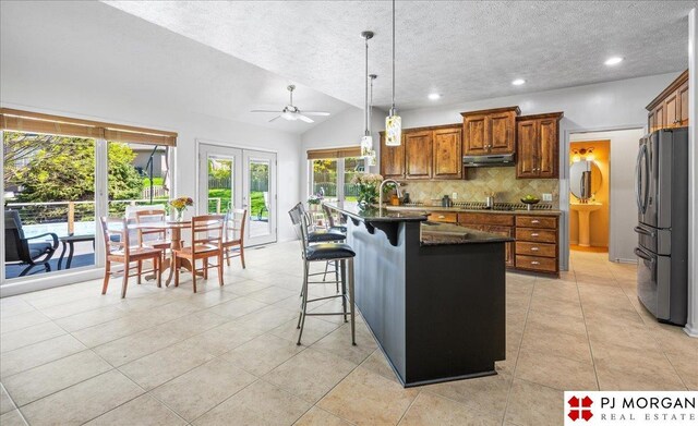kitchen featuring a textured ceiling, ceiling fan, under cabinet range hood, appliances with stainless steel finishes, and decorative backsplash