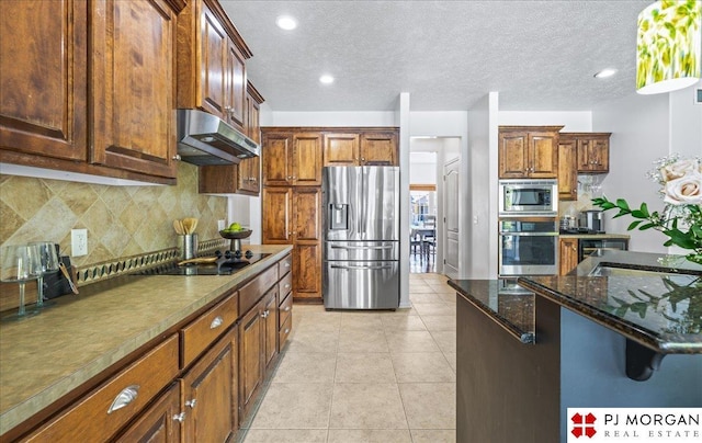 kitchen with under cabinet range hood, backsplash, light tile patterned floors, and appliances with stainless steel finishes