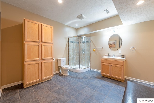 full bath with toilet, a shower stall, a textured ceiling, baseboards, and vanity