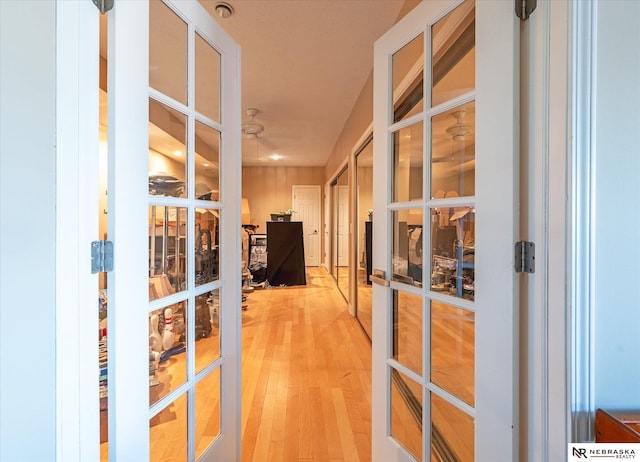 corridor with french doors and light wood-style floors