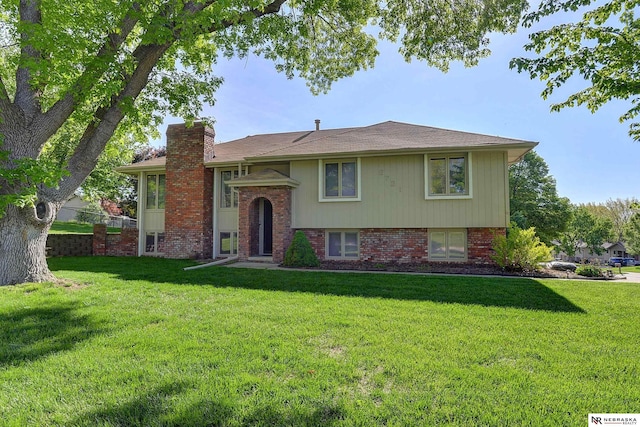 split foyer home with a front yard, a chimney, and brick siding
