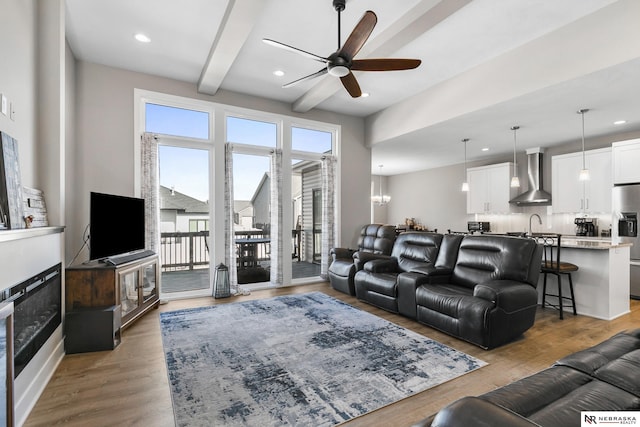 living area featuring a ceiling fan, recessed lighting, wood finished floors, and beam ceiling