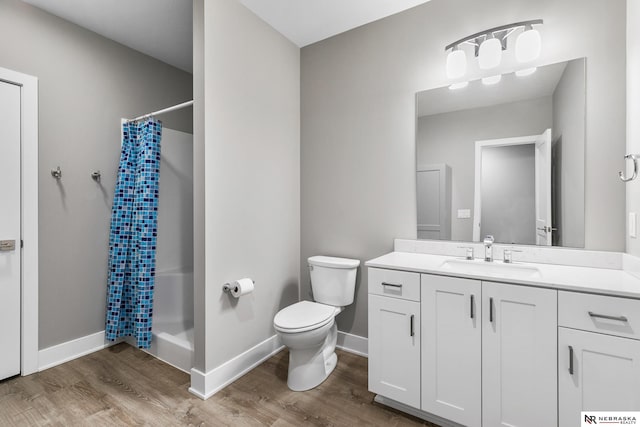 bathroom featuring toilet, a shower with shower curtain, wood finished floors, vanity, and baseboards